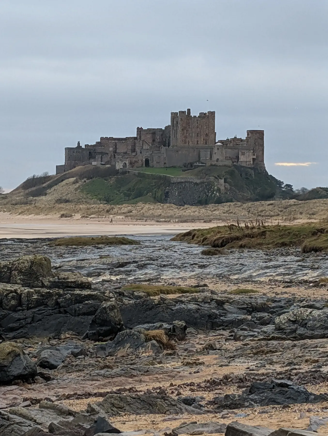Bamburgh Castle seen across the rocky shoreline