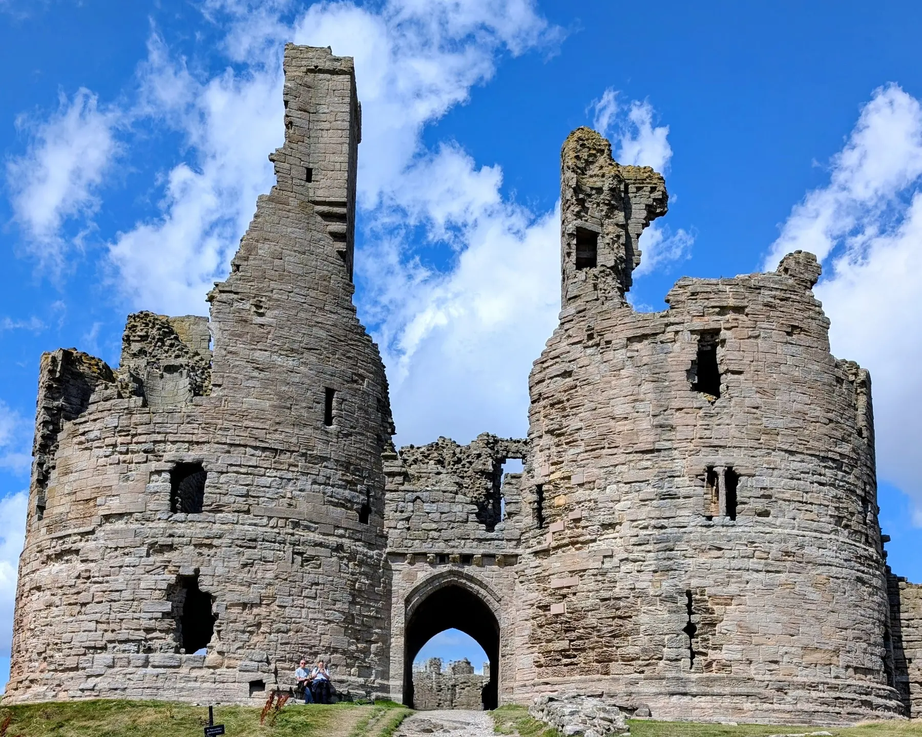 The ruins of Dunstanburgh Castle beneath a bright blue sky